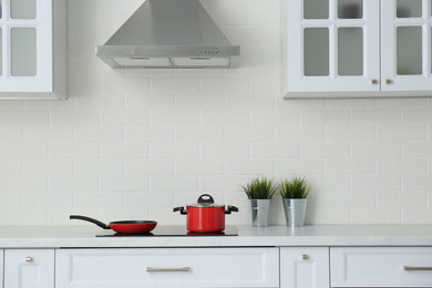 Photo of Saucepot and frying pan on induction stove in stylish kitchen interior