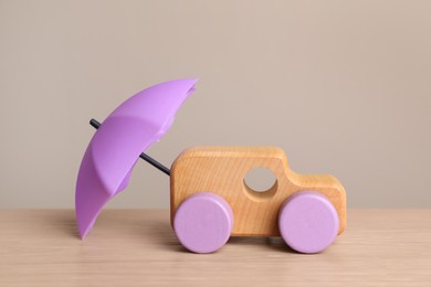 Photo of Small umbrella and toy car on wooden table