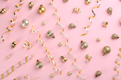 Photo of Shiny serpentine streamers and Christmas balls on pink background, flat lay