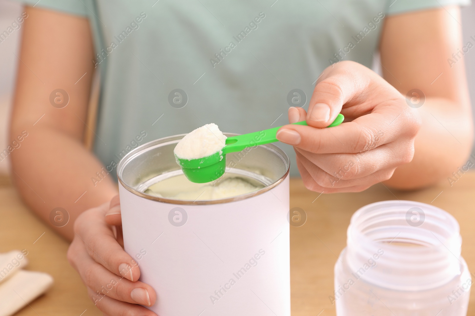 Photo of Woman with powdered infant formula at table, closeup. Preparing baby milk