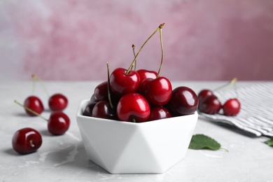 Bowl with ripe sweet cherries on marble table