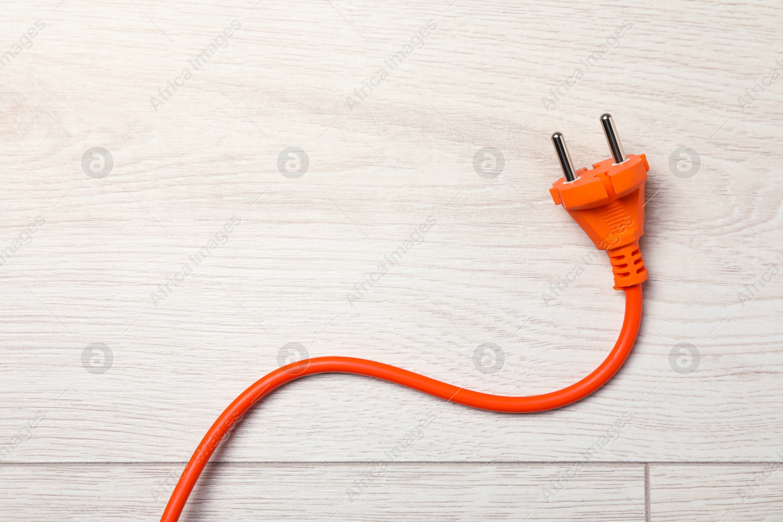 Photo of Extension cord on white wooden floor, top view. Space for text