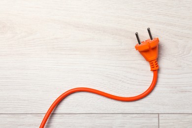 Extension cord on white wooden floor, top view. Space for text