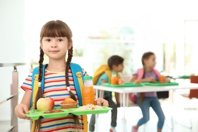 Photo of Girl holding tray with healthy food at school canteen