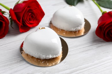 St. Valentine's Day. Delicious heart shaped cakes and roses on white wooden table, closeup