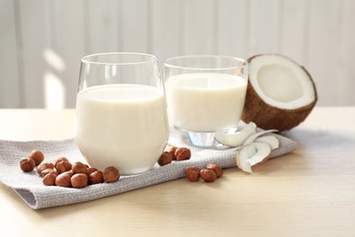 Photo of Glasses with milk substitute and nuts on kitchen table