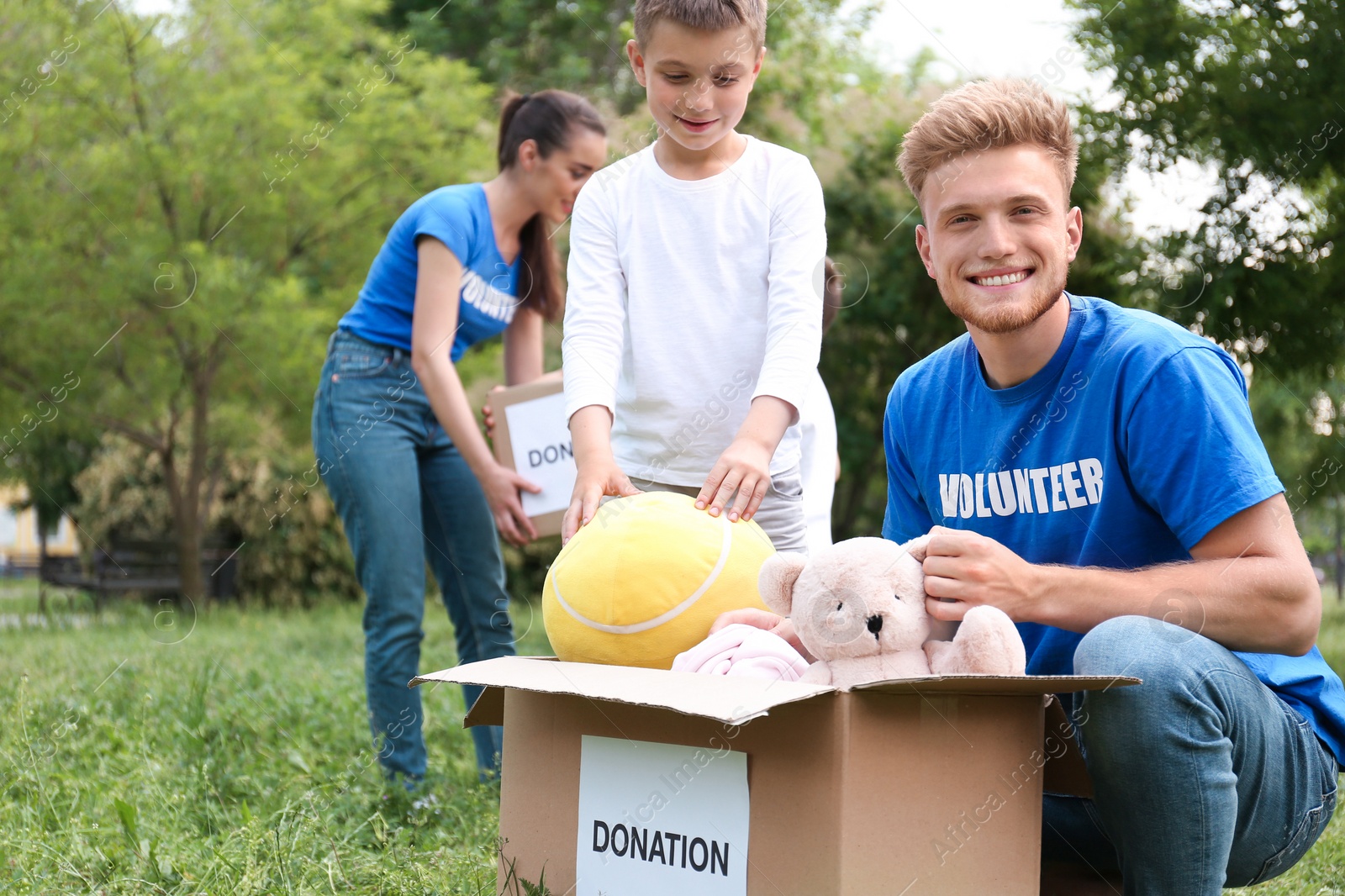 Photo of Volunteer and little boy with donation box in park