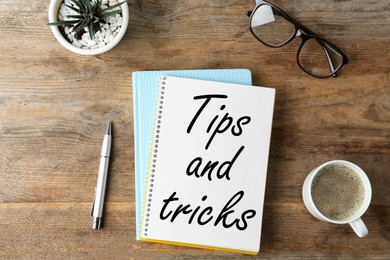 Notebook with text Tips and tricks on wooden table, flat lay