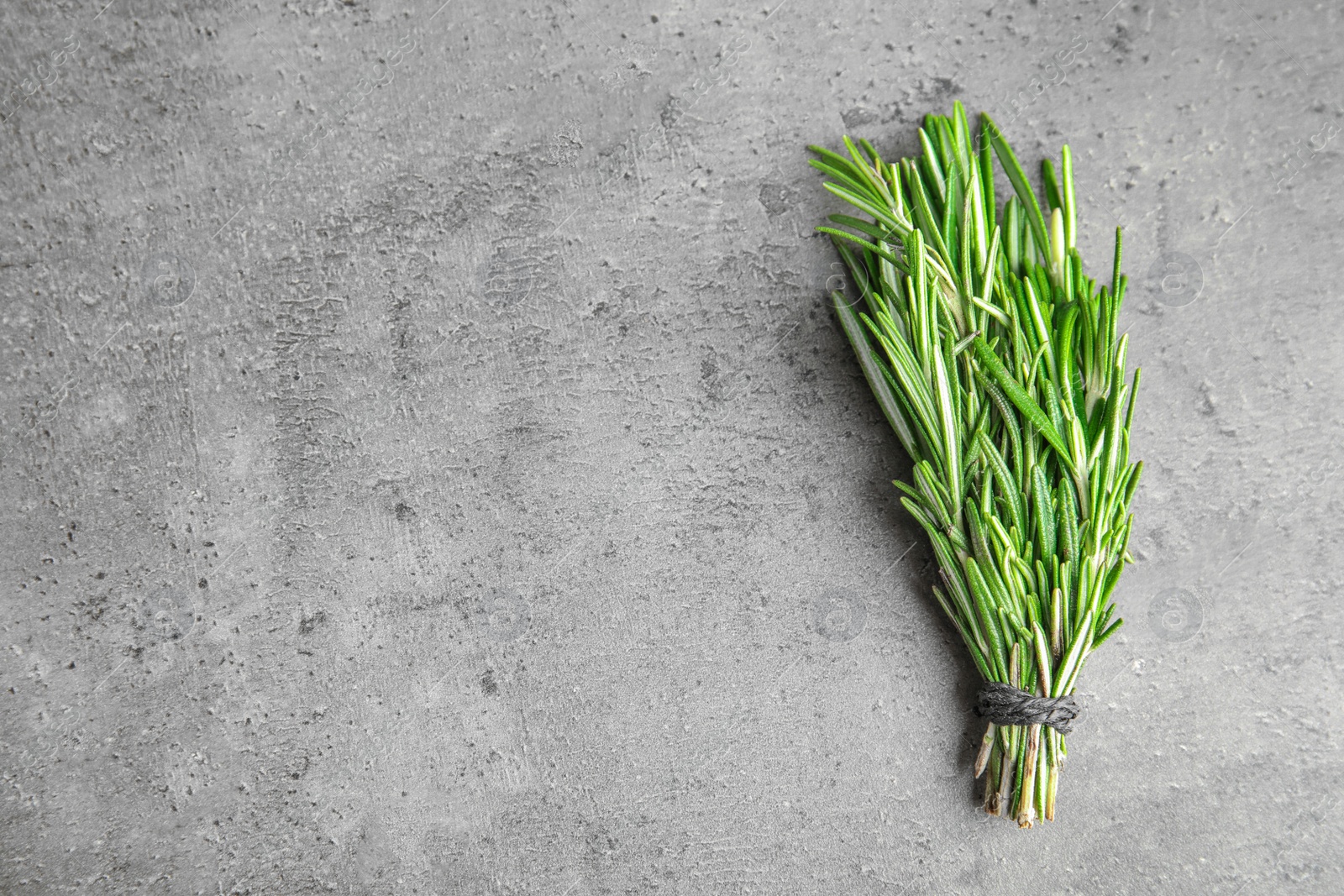 Photo of Bunch of fresh rosemary on grey table, top view with space for text