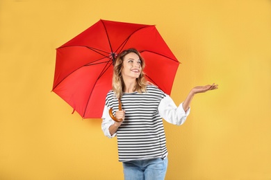 Woman with red umbrella on color background