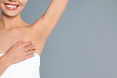 Young woman showing hairless armpit after epilation procedure on grey background, closeup. Space for text
