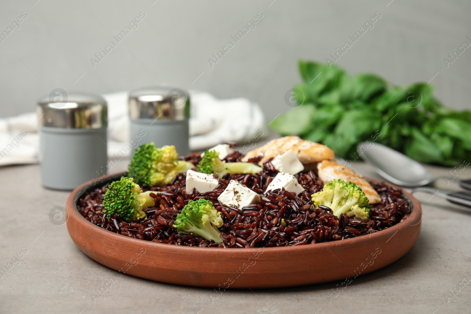 Photo of Plate with delicious cooked brown rice on grey table