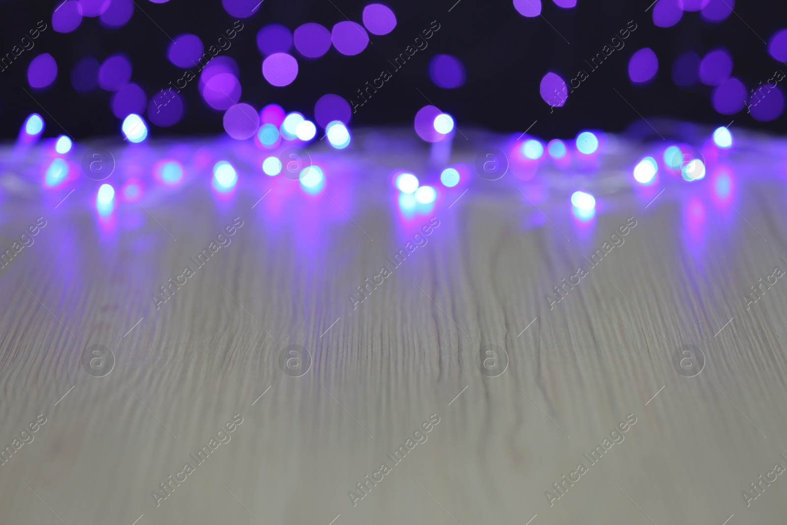 Photo of Empty white wooden table and blurred lights, bokeh effect. Space for design