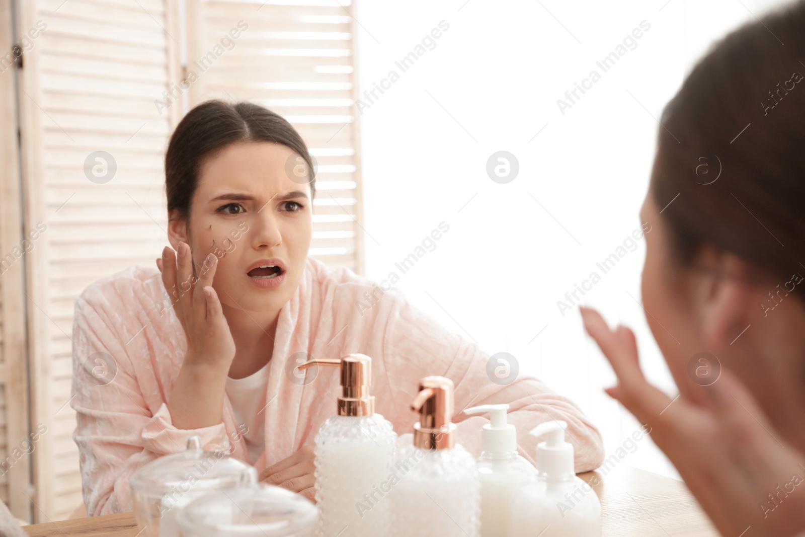 Photo of Beautiful woman with fallen eyelashes near mirror indoors