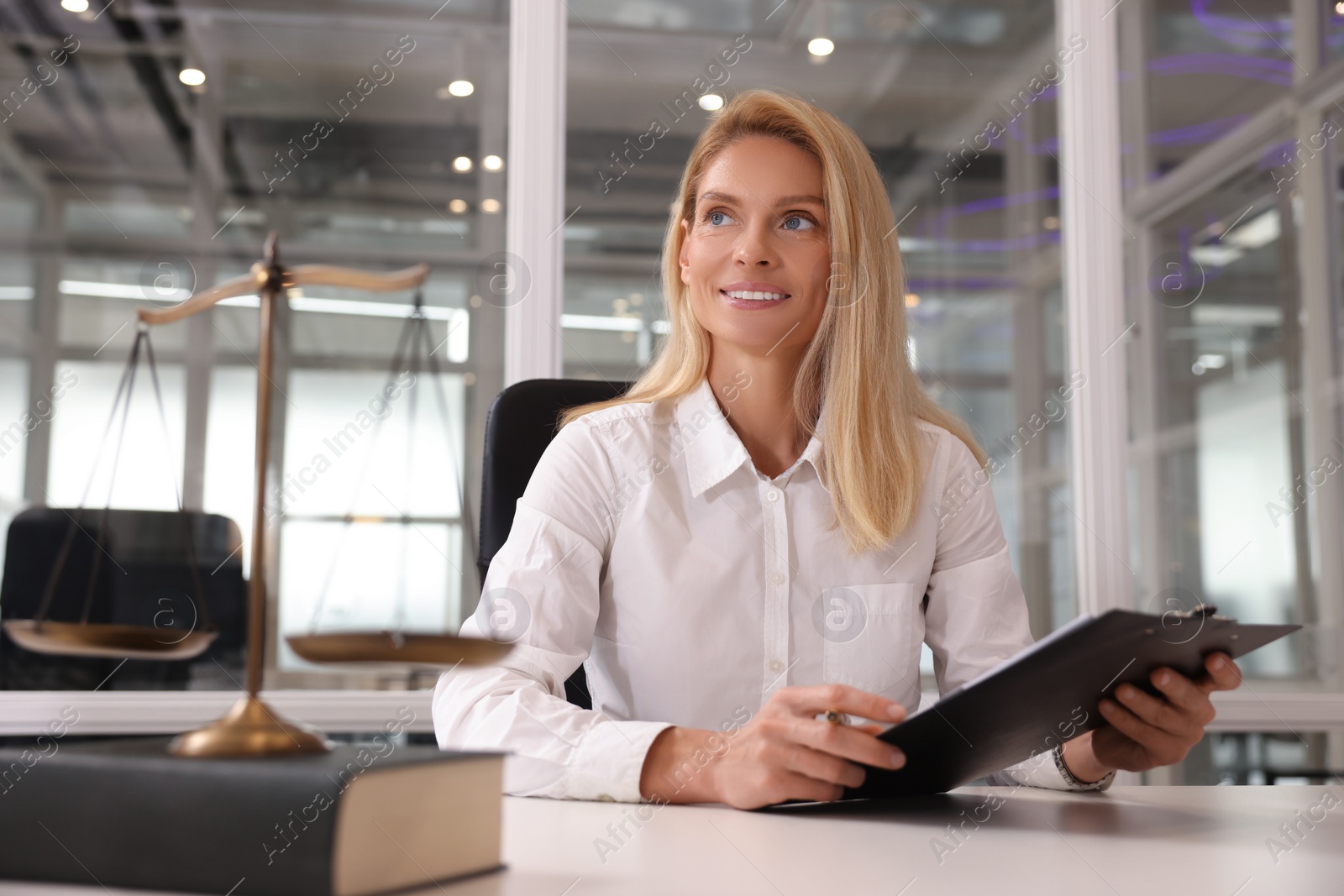 Photo of Smiling lawyer with clipboard at workplace in office