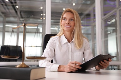 Photo of Smiling lawyer with clipboard at workplace in office