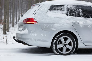 Photo of Car with winter tires on snowy road in forest