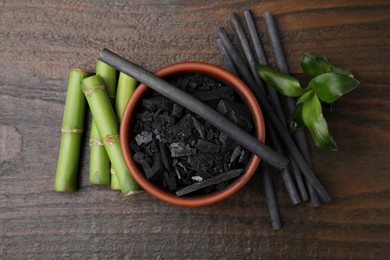 Photo of Fresh bamboo and charcoal on wooden table, flat lay