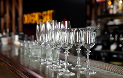 Photo of Different empty clean glasses on counter in bar