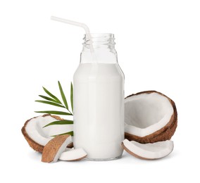 Photo of Glass bottle of delicious vegan milk, coconut pieces and green leaf on white background
