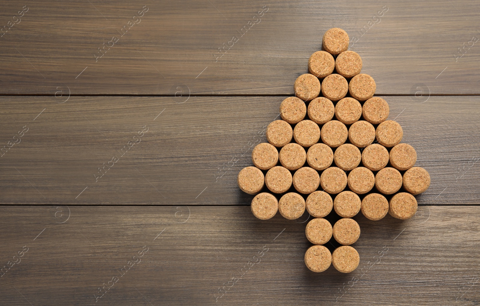 Photo of Christmas tree made of wine corks on wooden table, top view. Space for text