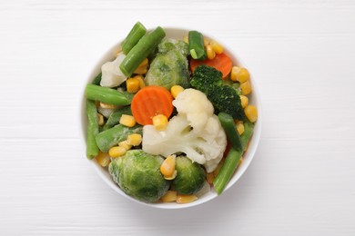 Photo of Mix of different frozen vegetables in bowl on white wooden table, top view