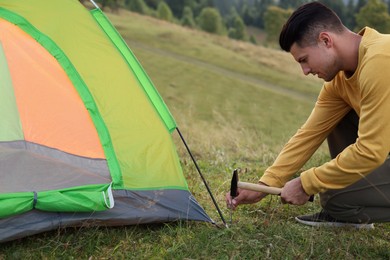 Photo of Man setting up camping tent on hill