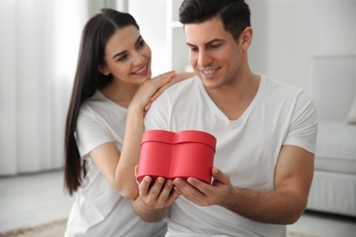 Photo of Lovely couple with gift box at home. Valentine's day celebration