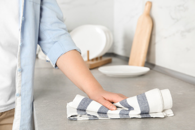 Photo of Woman wiping kitchen countertop with towel, closeup