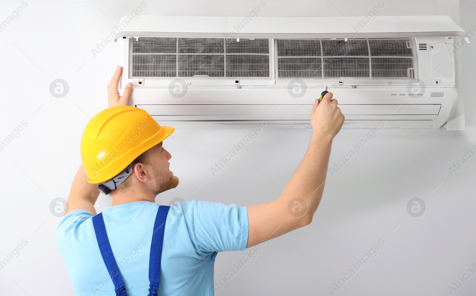 Photo of Professional technician maintaining modern air conditioner indoors