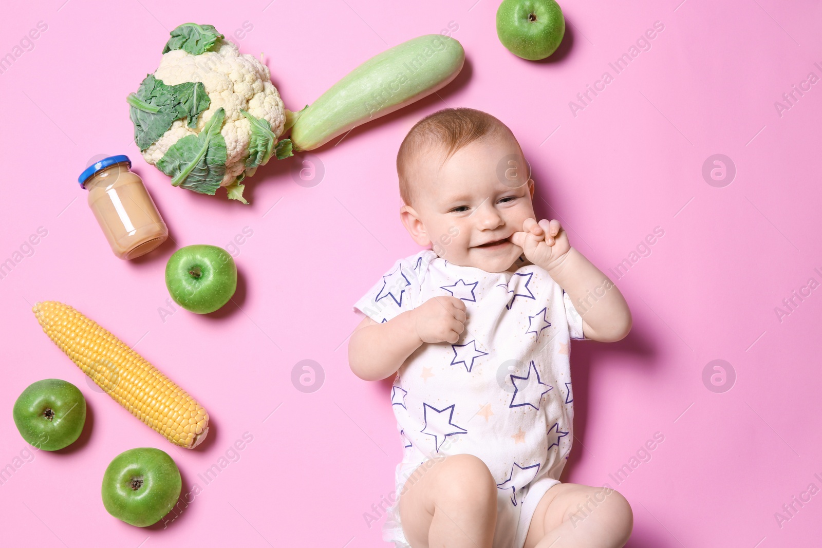 Photo of Cute little child with ingredients and puree in jar on color background, top view. Baby food