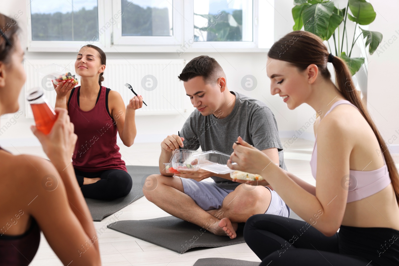 Photo of Group of people eating healthy food after yoga class indoors