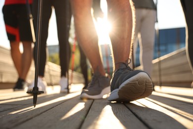 Photo of Group of people practicing Nordic walking with poles outdoors on sunny day, closeup