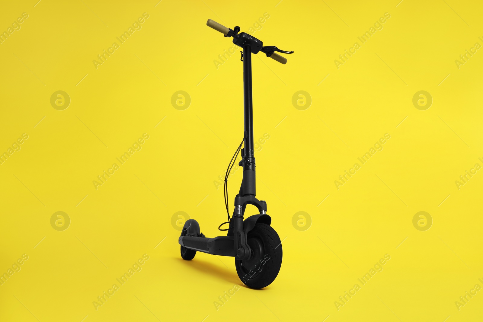 Photo of Modern electric kick scooter on yellow background
