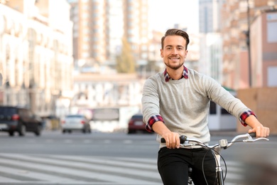 Handsome happy man riding bicycle on city street