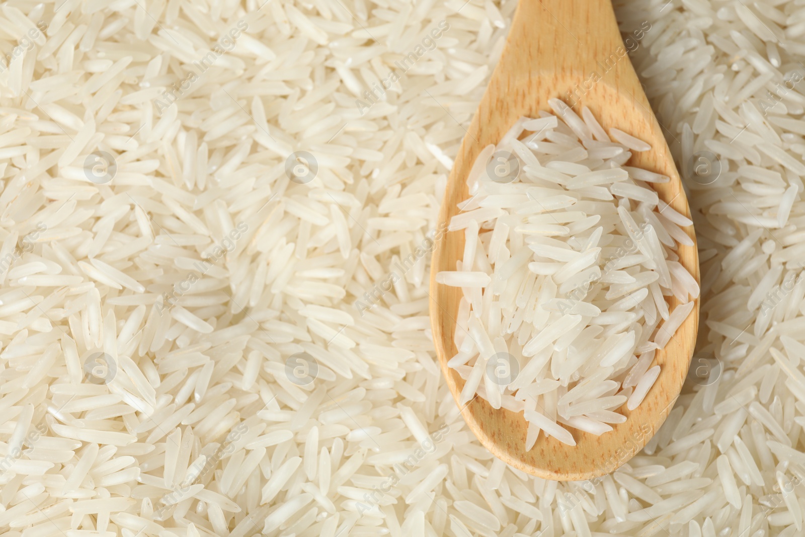 Photo of Raw basmati rice and spoon as background, top view. Space for text