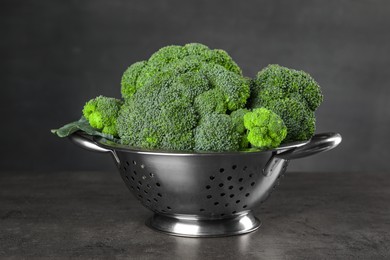 Colander with fresh raw broccoli on grey table