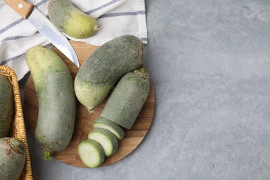 Photo of Green daikon radishes and knife on light grey table, flat lay. Space for text