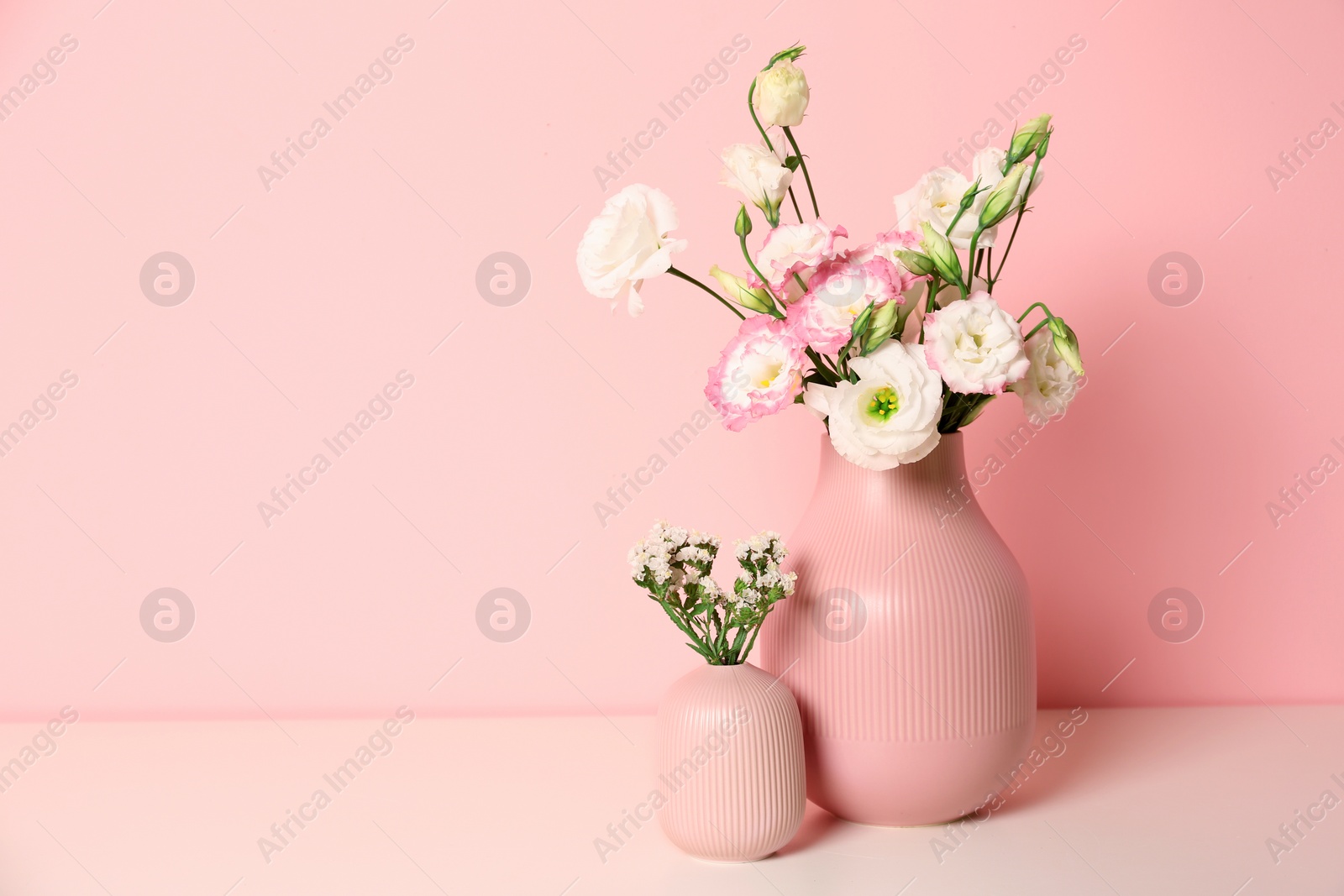 Photo of Beautiful flowers in vases and space for text on color background. Element of interior design