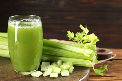 Photo of Glass of celery juice and fresh vegetables on wooden table, closeup