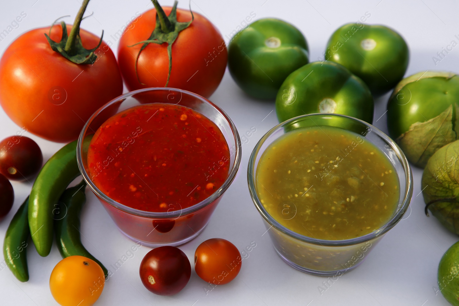 Photo of Bowls with delicious salsa sauces and ingredients on white background, closeup