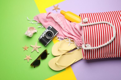 Photo of Stylish bag with beach accessories on color background, flat lay