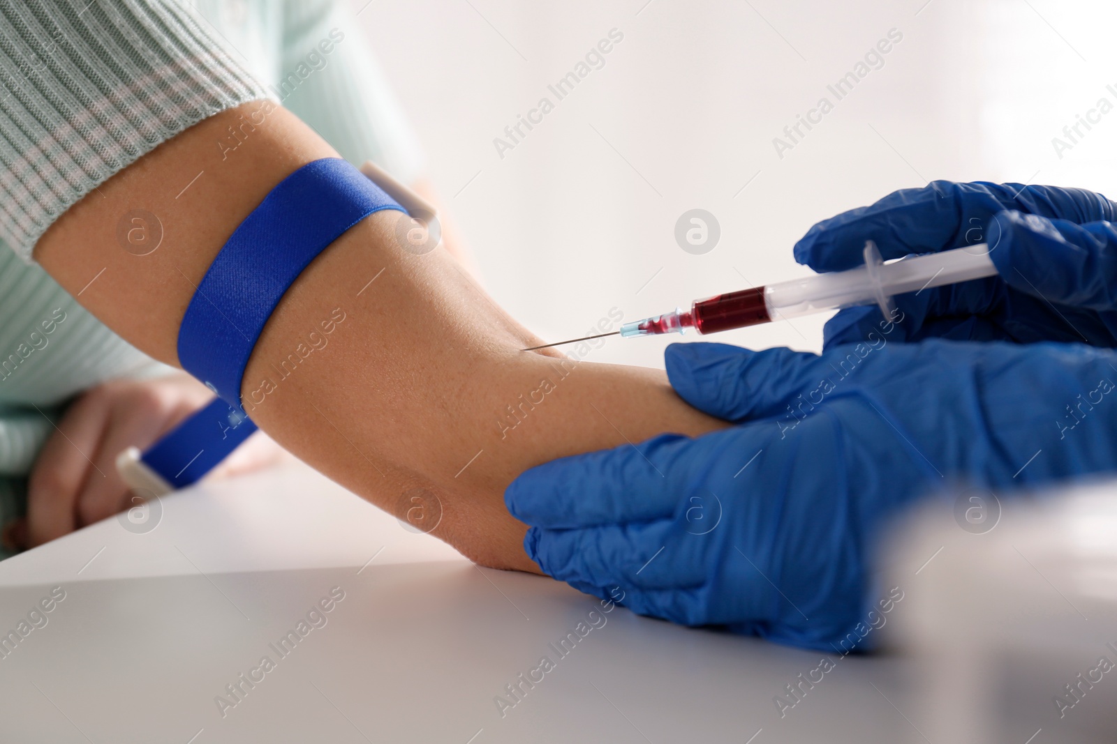 Photo of Nurse drawing blood sample from patient in clinic, closeup