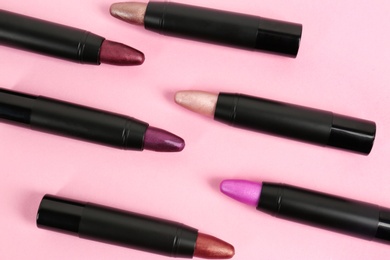 Photo of Set of bright lipsticks in black tubes on pink background, flat lay