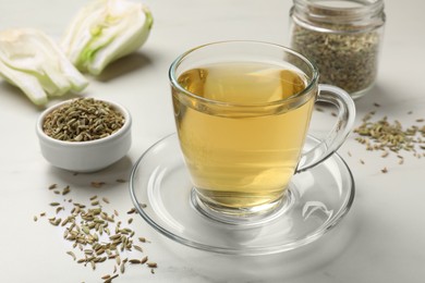 Photo of Aromatic fennel tea, seeds and fresh vegetable on white table, closeup