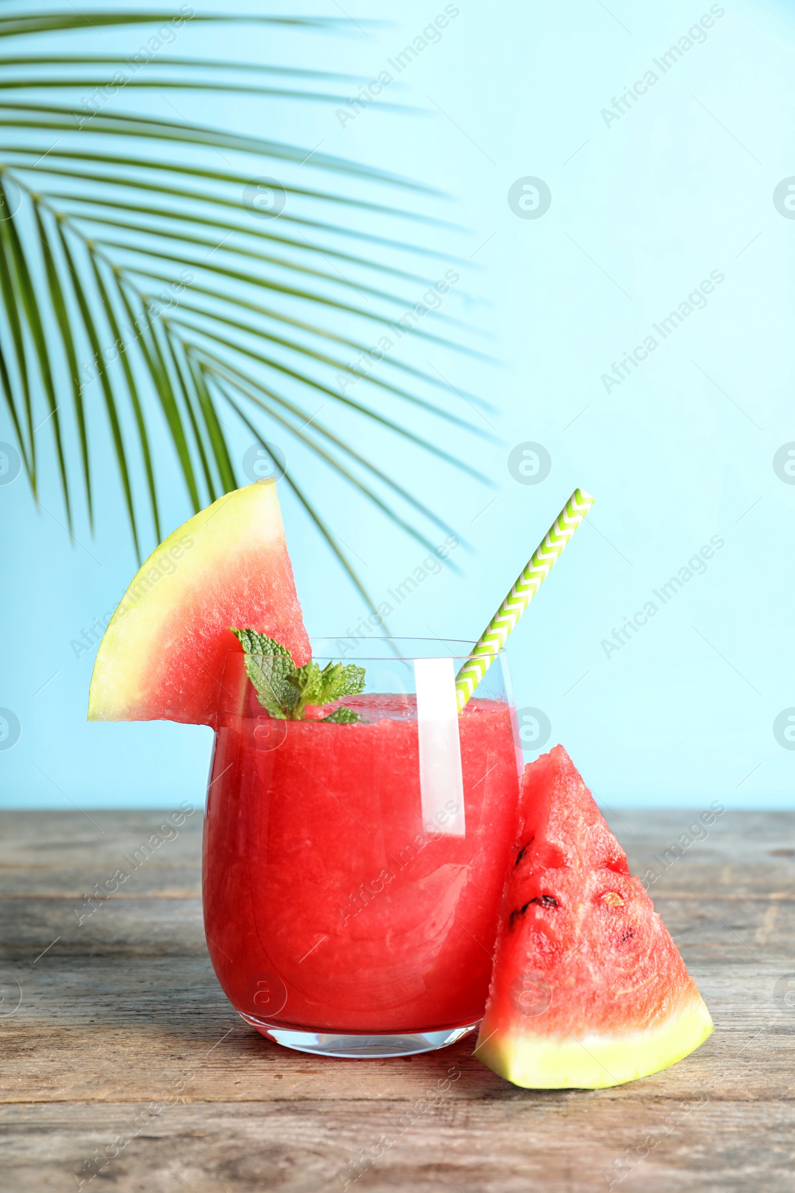 Photo of Tasty summer watermelon drink in glass and sliced fruit on table