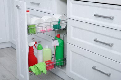 Photo of Open drawer with different cleaning supplies in kitchen