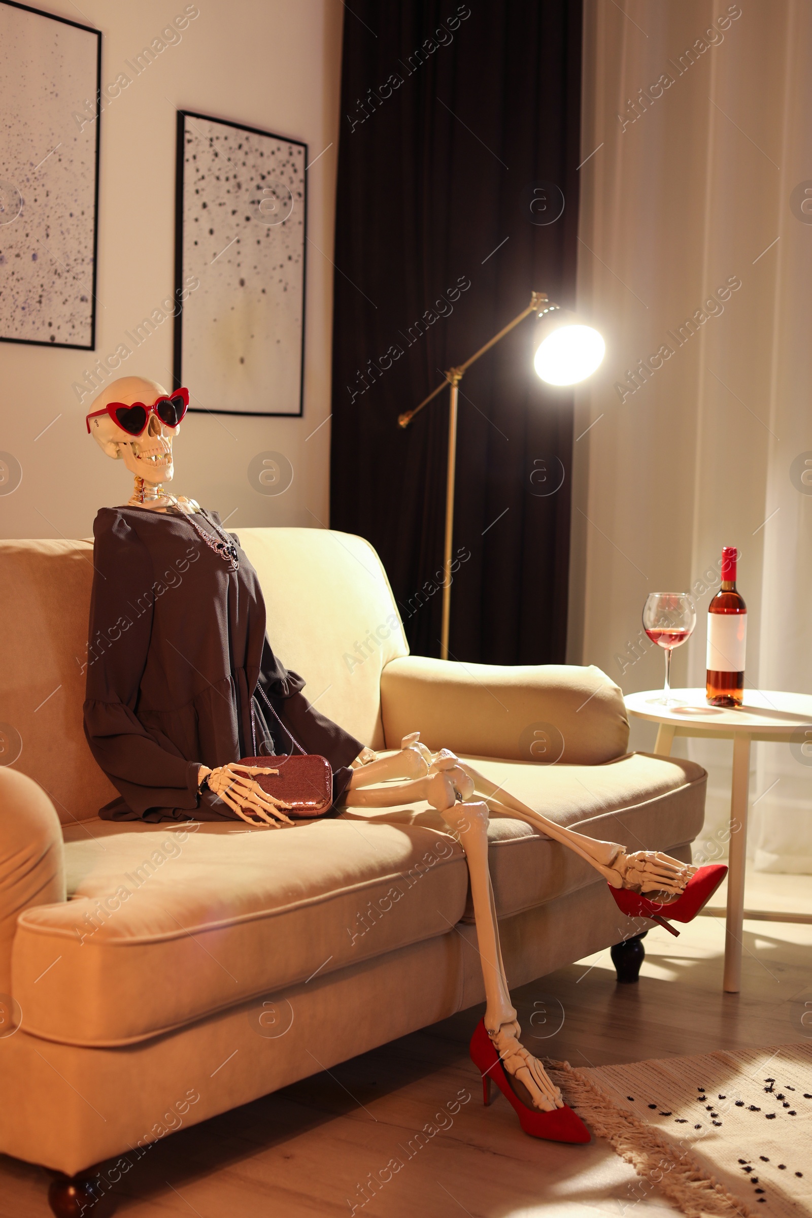 Photo of Skeleton in dress sitting on sofa at home