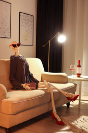 Skeleton in dress sitting on sofa at home
