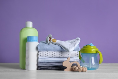 Photo of Children's accessories and stack of clothes on white wooden table